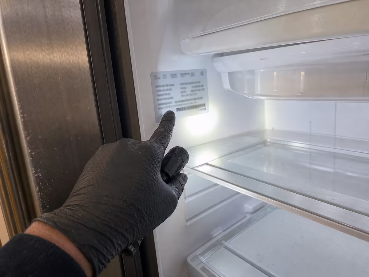 Close-up of a Sub-Zero model and serial number tag inside the fresh-food compartment on the upper left wall